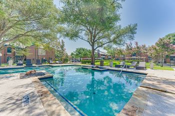 A swimming pool surrounded by trees and a grassy area.